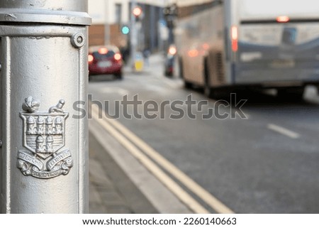 Dublin city logo on a lamp post , city traffic out of focus in the background.