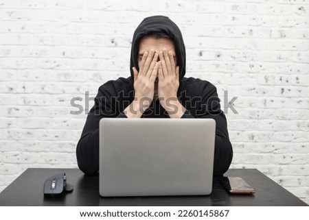 Frustrated guy feeling bad after losing the game. Unhappy man in hoodie sitting at the computer at home