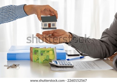 Real estate agent and customer  signing a contract to buy a house with land and insurance. Mortgage Loan Agreement. A delivering a sample of a model house to the customer. Concept.