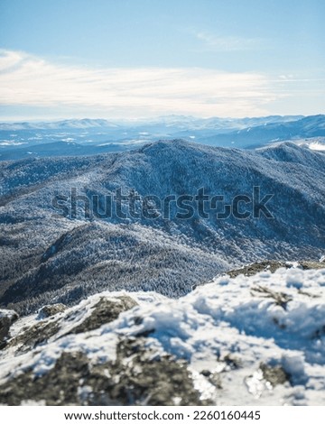 A view of the snow covered hills from the top of the summit of Camel's hump in the green mountains of Vermont. Royalty-Free Stock Photo #2260160445