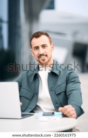 Portrait of confident smiling freelancer using laptop computer working online sitting at workplace. Successful business 