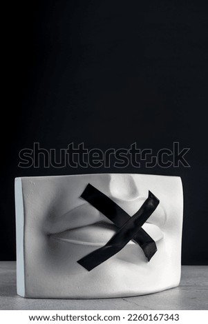 Silence sign. Plaster statue of lips with black tape. Keep quiet.