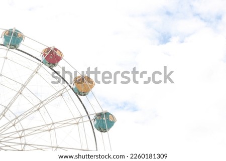 Ferris wheel above white clouds and blue sky