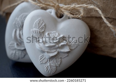 the plaster heart with the image of a rose is made of plaster by hand Royalty-Free Stock Photo #2260185271