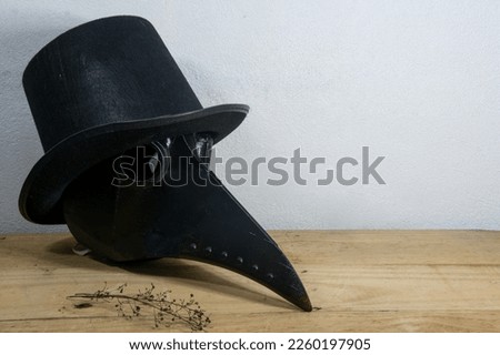 Mask of doctor plague with hat on table