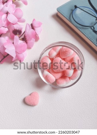 Pink and white gummy hearts with strawberry flavored. Served on transparent glass. Sweet taste. Isolated background in white