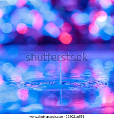 A drop falls into a thick liquid with a blue-violet background. Abstract colorful background