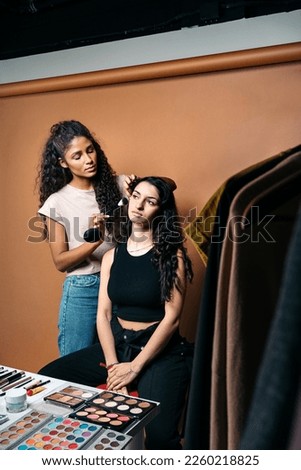 Stock photo of cool makeup artist doing makeup to her client in studio.