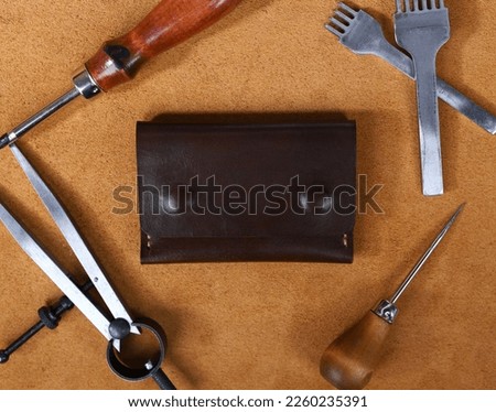 Dark Brown Leather Wallet Isolated on Leather with Leather Crafting Tools
