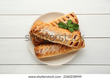 Fresh tasty puff pastry with sugar powder and mint on white wooden table, top view Royalty-Free Stock Photo #2260238949