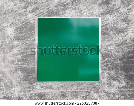 Green metal sign on concrete wall