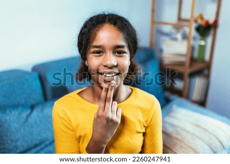 Beautiful smiling black deaf girl using sign language at home
