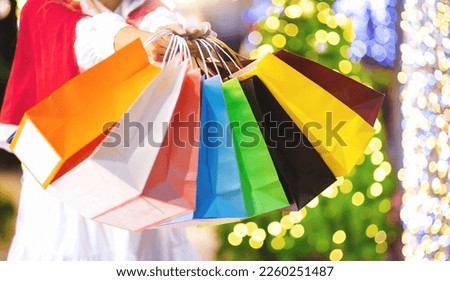 Female hand holding many colorful shopping bags on bokeh background