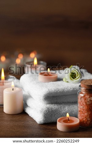 Beautiful spa composition with burning candles and flower on wooden table Royalty-Free Stock Photo #2260252249