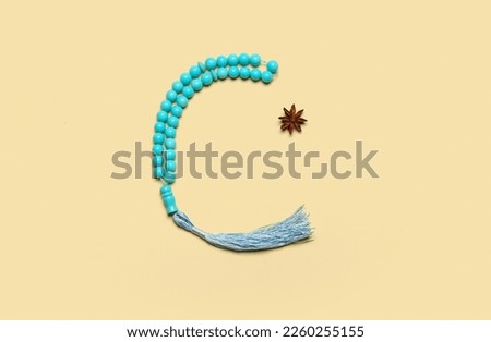 Prayer beads in shape of crescent and anise for Ramadan on color background Royalty-Free Stock Photo #2260255155