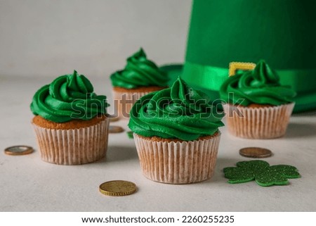 Tasty cupcakes for St. Patrick's Day, leprechaun hat and coins on white background