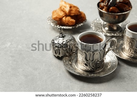Tea, baklava dessert and date fruits served in vintage tea set on grey table, space for text