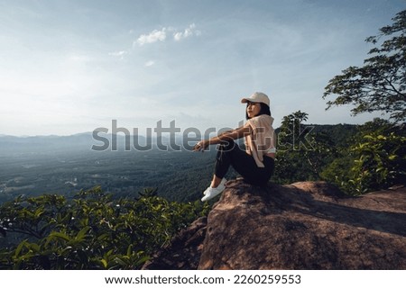 Asian girl on the mountain, on the edge of the cliff, looking back at the sunset very beautiful sky stay with nature on vacation