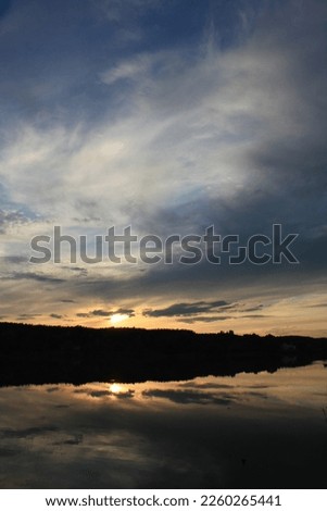 Sunset cloudy sky reflected in forest lake landscape photo. Beautiful nature scenery photography with blur background. Idyllic scene. High quality picture for wallpaper, travel blog, magazine, article