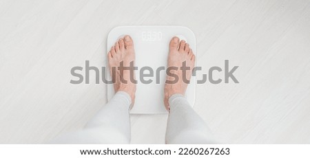 Female bare feet standing on a scales Royalty-Free Stock Photo #2260267263