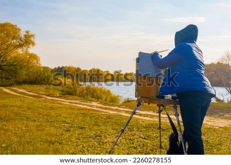 Artist paint an autumn landscape with a river in central Russia. Artist in the open air