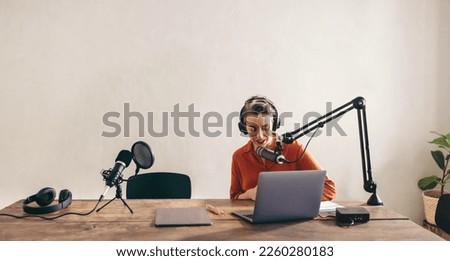 Female radio dj preparing a live audio broadcast with a laptop. Woman recording a live internet podcast in her studio. Female content creator live streaming on her social media channel.