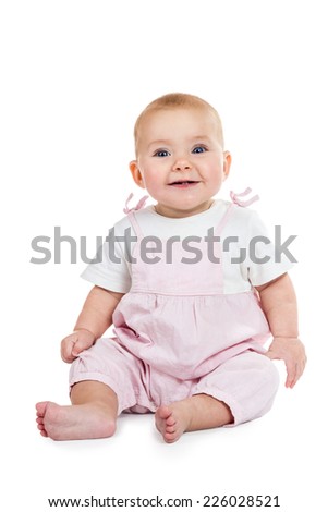 Smiling baby in pink jumpsuit sitting on the floor isolated on white background