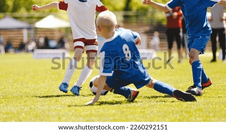 Soccer football tackle moment. Skill of tackling in soccer game.  Kids kicking soccer ball on grass pitch. Kids footballers in a duel. Running school age boys.