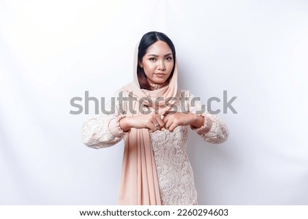 Beautiful Asian Muslim woman wearing a hijab with hand gesture pose rejection or prohibition with copy space