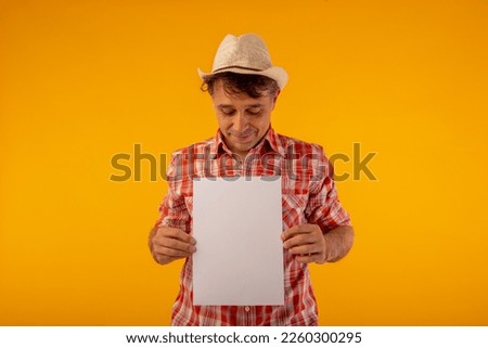 Adult man with hat and checkered shirt holding a blank cardboard on which you can put messages