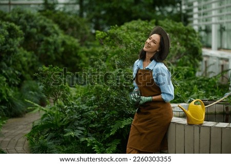 Positive smiling woman gardener carrying flowerpots in hand selective focus