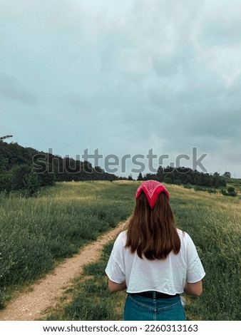 a teenage girl in denim skirt and white top walking in park of Bydgoszcz
