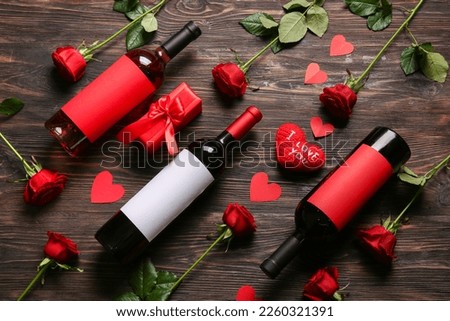 Bottles of wine, rose flowers and hearts on wooden background. Valentine's Day celebration