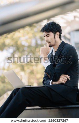 Asian male businessman looking at financial graph in laptop computer, businessman analyzing business strategy.