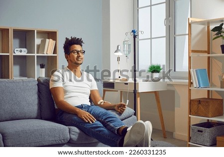 Young Afro American man with vitamin deficiency receiving modern intravenous anti stress nutrient and hydration therapy through sterile IV drip line infusion system for healthy body and stress relief Royalty-Free Stock Photo #2260331235