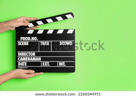 Second assistant camera holding clapper board against chroma key background, closeup. Space for text