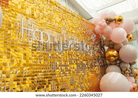 A large festive photo zone for a birthday, decorated with gold sequins, pink, gray and gold balloons of different sizes. Celebrating concept