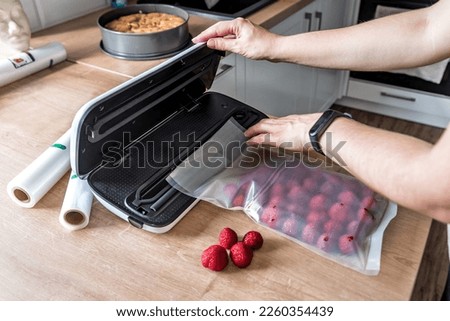 Woman use vacuum sealer packing machine for long-term storage of products. Vacuum strawberries packaging for long-term storage. Royalty-Free Stock Photo #2260354439