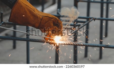 Hands of a welder are welding steel for the structure of the building. Royalty-Free Stock Photo #2260360197