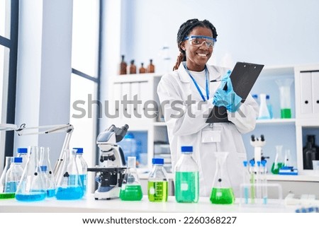 African american woman scientist writing report working at laboratory