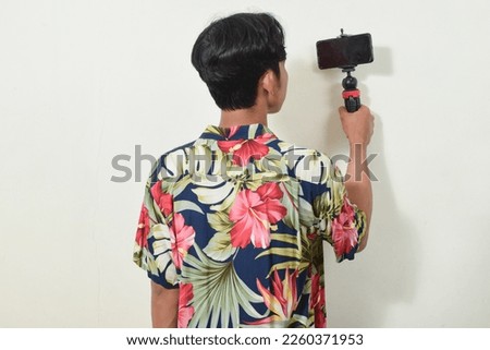 portrait of asian man holding smartphone or camera. Indonesian men's gestures are taking pictures, communicating, recording videos, video calls, or selfies. content creator illustration