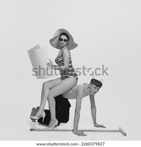 Portrait of beautiful young woman in swimming suit sitting on back of young shirtless sailor isolated on white background. Concept of holiday, work, retro fashion, vintage style. Black and white
