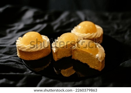 Lemon tartlets on a black background. An exquisite European dessert with fruit filling.