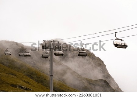 Amusement park rides, excursion with ski lift in the fog. Natural park background, abstract scenic landscape in mountains. Vacation trip ideas Royalty-Free Stock Photo #2260381031
