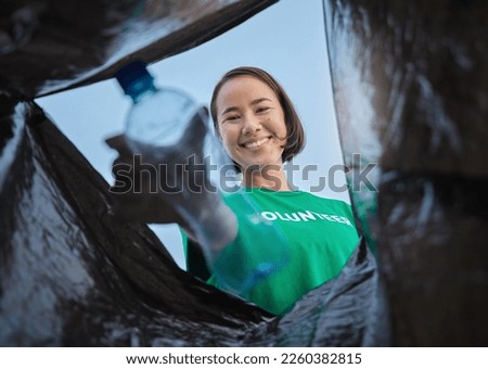 Recycle, bottle and asian woman with view in bag, sustainability and cleaning plastic pollution, earth day and help with community. Saving the environment, charity and people putting trash in garbage Royalty-Free Stock Photo #2260382815