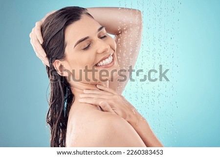 Face, skincare shower and water splash of woman in studio isolated on a blue background. Beauty, facial and happy female model washing, cleaning or bathing for hygiene, wellness and healthy skin.