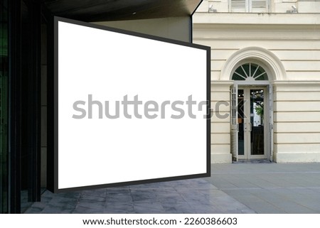 Large horizontal blank advertising poster billboard banner mockup in front of building entrance in urban city; digital light box display screen for OOH media