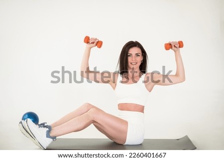 Young beautiful sportswoman. girl goes in for sports with dumbbells. sports girl on a gray background. High quality photo