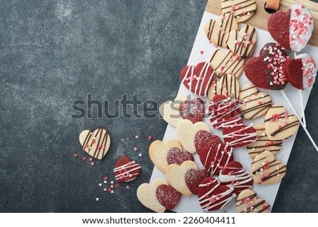 Valentines day cookies. Shortbread cookies inside sweet red heart with chocolate glaze on pink plate on grey background. Mothers day. Womans day. Sweet holidays baking. Valentines day card. Top view.
