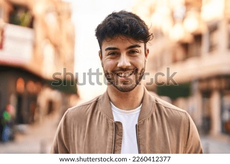 Young hispanic man smiling confident standing at street Royalty-Free Stock Photo #2260412377